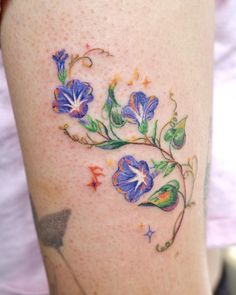 a woman's thigh with flowers and stars on the bottom part of her leg