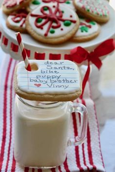 cookies and milk are on a table with red and white striped napkins that have writing on them