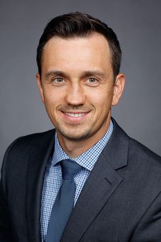 a man in a suit and tie smiling at the camera