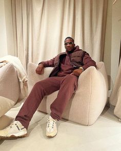 a man sitting in a chair with his feet up on the floor and wearing white shoes