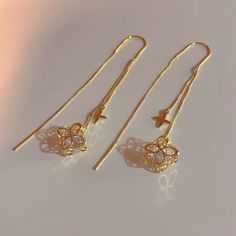 two pairs of gold tone earrings with dangling hooks and star shaped crystal stones on them