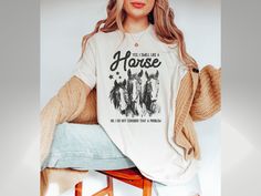 a woman sitting on top of a stool wearing a horse t - shirt