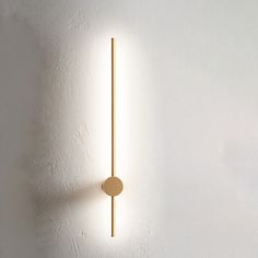 a white wall with a light on it and a round object hanging from the side