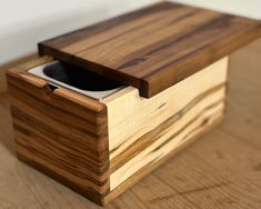 a wooden box with a cell phone in it on top of a wood floor next to a wall