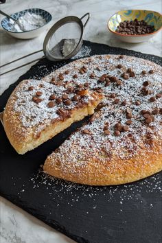 a cake that has been cut into pieces and is on a black board with powdered sugar