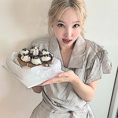 a woman holding a tray with cupcakes on it