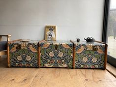 two suitcases sitting next to each other on top of a wooden floor in front of a window