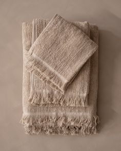 two towels folded on top of each other with fringes around the edges and bottom