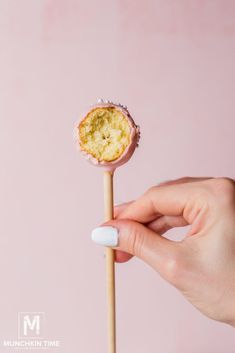 a hand holding a small cake on a stick