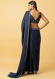 Featuring a captivating navy blue modal satin pre-draped saree with an intricately embroidered border. Teamed with a blue modal satin sleeveless blouse embellished with hand-embroidered mirror work, gota patti and zardosi floral motifs. Perfect for wedding reception or Sangeet. This saree is pre stitched saree for your convenience. Composition : Saree and Blouse - Modal satin Care: Dry Clean Only and Vacuum Storage This product can be customized for sleeves, length of blouse and neckline Delivery : 2-4 weeks as the product is hand crafted. Check Size Guide or choose MySize for free customisation (All Sizes above XL can be made at 15% additional cost) For more information and sizes please contact fabiliciousfashion@gmail.com or visit our Copenhagen studio. About the Designer : From being a Elegant Blue Dola Silk Pre-draped Saree, Blouse Modal, Pre Draped Saree, Pre Stitched Saree, Draped Saree, Stitched Saree, Saree And Blouse, Vacuum Storage, Drape Saree