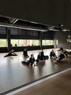 a group of people sitting on top of a wooden floor in front of a mirror