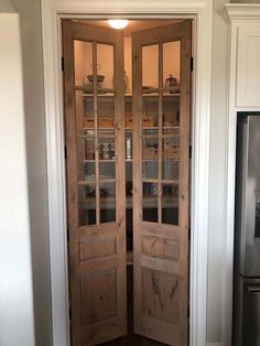 an open wooden door in a kitchen next to a refrigerator