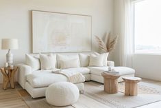 a living room filled with white furniture and a large painting on the wall above it