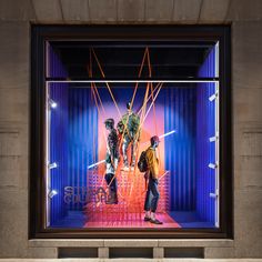 two mannequins dressed in costumes on display behind a glass case with neon lights