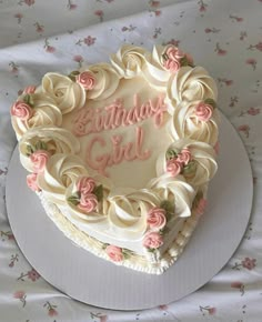 a heart shaped birthday cake sitting on top of a white tablecloth covered table cloth