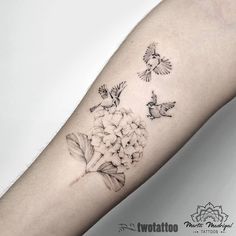 a woman's arm with flowers and birds tattoo on the left side of her arm