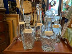 three glass bottles with labels on them sitting on a table in front of a mirror