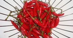 a pile of red hot peppers sitting on top of a white plate with toothpicks