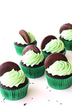 chocolate cupcakes with green frosting on a white surface