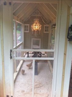 the inside of a chicken coop with an open door and chandelier hanging from the ceiling