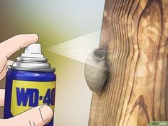 a person spraying wood glue on a wooden fence with a spray bottle next to it