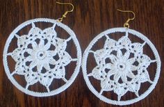 two crocheted white circular earrings on a wooden table