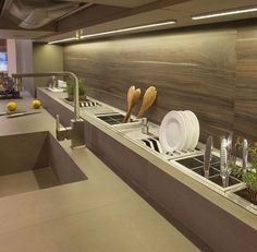 there are many plates and silverware on the counter in this kitchen area, along with plants