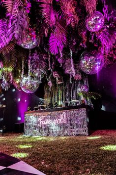 an outdoor event with purple lighting and palm trees in the background, decorated with disco balls