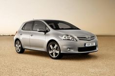 a silver toyota car parked on top of a sandy beach