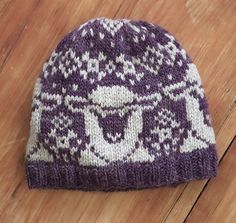 a purple and white knitted hat sitting on top of a wooden floor