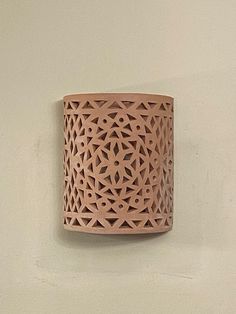 a wall mounted light on the side of a white wall with an intricate design in it