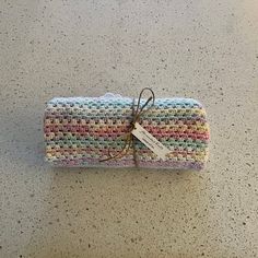 a multicolored crocheted cloth wrapped in twine with a tag on it