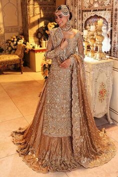 a woman standing in front of a mirror wearing a gold gown and headpieces