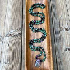 Rainbow Fluorite Mala Necklace with Green/Pink Jasper Beads & Black Onyx Beads.  This beautiful Mala necklace is hand strung and hand knotted by us. It features a total of 108 natural 8 mm green/pink Jasper and black Onyx beads.  The beads are strung on a green colored nylon cord and hand knotted between each bead. It features a large polished Rainbow Fluorite pendant. The overall beaded length is approximately 40-42 inches. The stones used for this Mala are strong abundance and protection stones: * Rainbow Fluorite: Clarity, Focus, Protection, Balance. * Green Jasper: Abundance, Healing, Emotional Support.  * Black Onyx: Protection, Grounding, Focus. Our Malas are made of natural gemstones so there may be small variations in colors, shapes, and sizes. Our Malas come with a satin drawstrin Obsidian Beaded Jewelry For Healing, Black Natural Stones Beads For Healing, Healing Onyx Jewelry With 108 Beads, Spiritual Handmade Onyx Beaded Necklaces, Spiritual Onyx Beaded Necklaces With 8mm Beads, Spiritual Onyx Beaded Necklaces, Black Natural Stones Beads For Meditation, Spiritual Black Beaded Necklaces, Spiritual Onyx Beaded Necklace