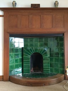 a fireplace in a room with green tiles