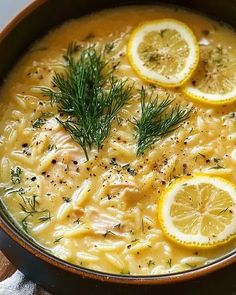 a bowl full of soup with lemons and dill on the side, sitting on a table