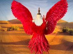 a mannequin with red feathers and a white dress on display in the desert