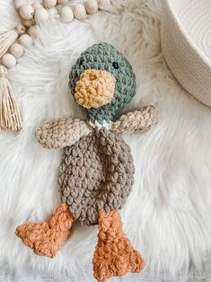 a crocheted duck laying on top of a white rug