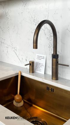 a kitchen sink with a brass faucet and soap dispenser