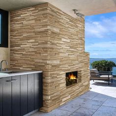 an outdoor fireplace is built into the side of a building with a view of the ocean