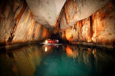 two people in a small boat on the water inside a cave with large rock walls