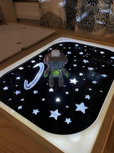 a small toy is sitting on top of a black surface with white stars and planets