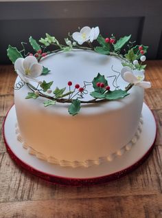 a cake decorated with holly and white flowers