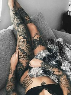 a woman laying on top of a couch covered in tattoos