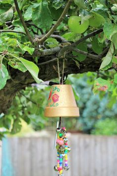 a lamp hanging from a tree branch with beads on it and a bird feeder underneath