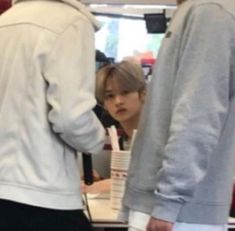 two people standing in front of a table with cups on it and one person wearing a hoodie