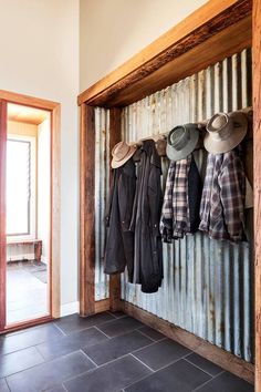 the interior french doors are open to show hats and coats hanging from hooks on an old door