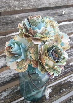 a vase filled with paper flowers sitting on top of a wooden bench