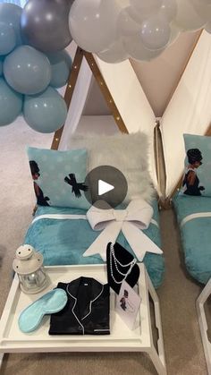 two couches with blue and white pillows on them in front of some balloons that look like they have been set up for a party