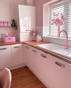 a kitchen with white cabinets and pink accessories